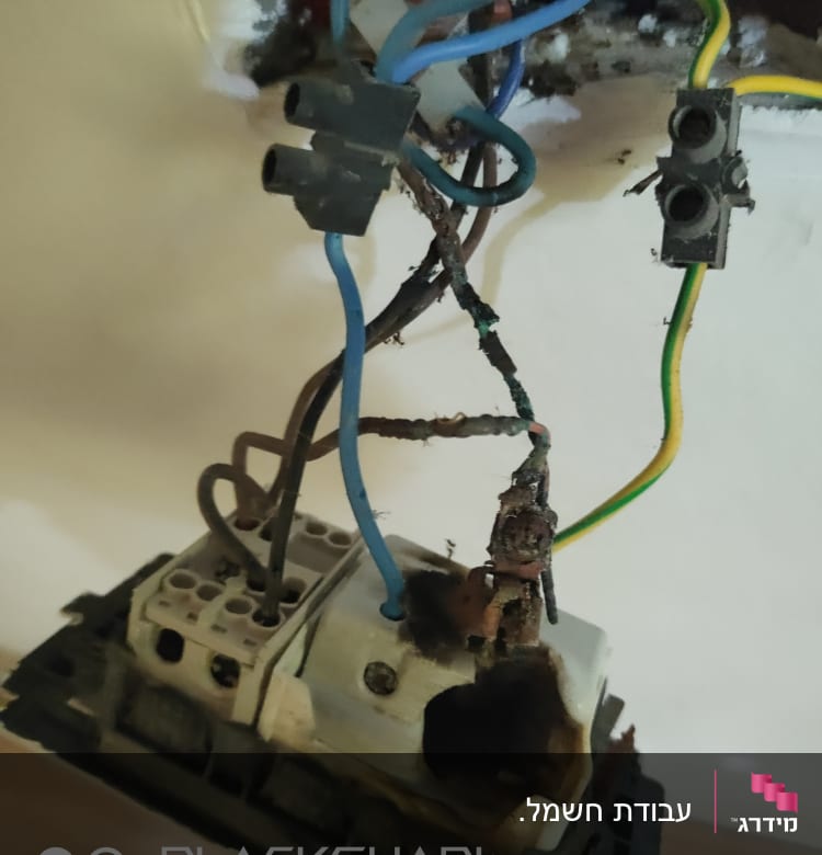 חוטי חשמל חשופים ומחוברים לשקע פגום